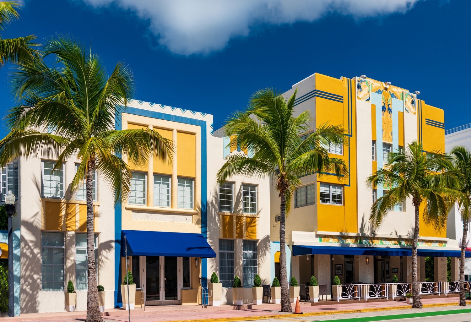 A colorful Art Deco building with palm trees in front of it.