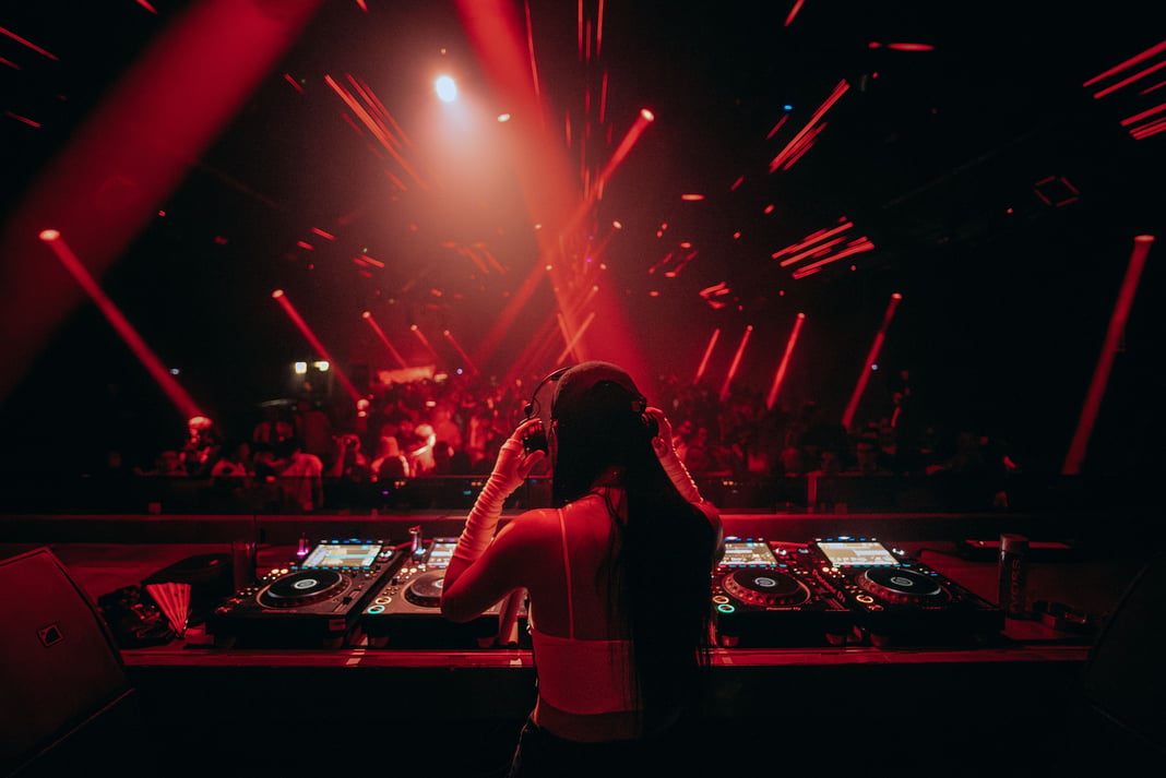 Energetic nightclub with female DJ mixing music under vibrant red lights